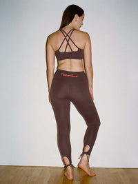 Back view of model wearing Star Bra in Brown, featuring intersecting shoulder straps for support.