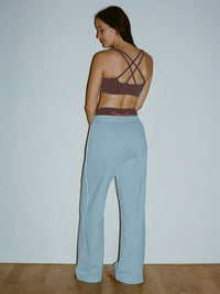 Back view of model wearing Star Bra in Maroon with intersecting straps, paired with relaxed fit pants.