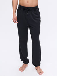 Model standing in Stratus Sweatpant in Black, featuring a relaxed fit and elastic cuffs for comfort.