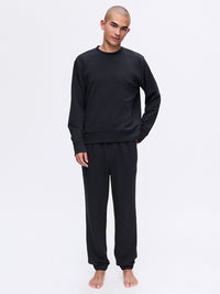 Model standing in relaxed pose wearing Stratus Sweatshirt in Black, featuring a heavyweight, ultra-soft fabric.