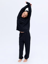 Model stretching in Stratus Sweatshirt, heavyweight and ultra-soft for cozy warmth in cooler weather.