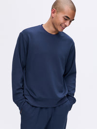 Model smiling while wearing Stratus Sweatshirt in Navy, featuring a relaxed fit for comfort in cooler weather.