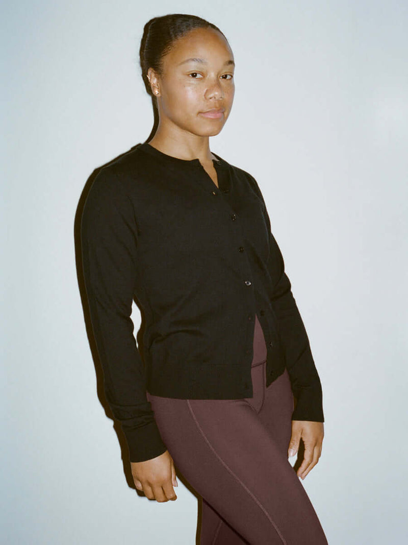 Model wearing Sugar Cardigan in Black, lightweight knit with hand-embroidered OV signature.