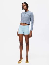 Model standing in light blue shorts and Sugar Cardigan in Grey, featuring OV signature embroidery.