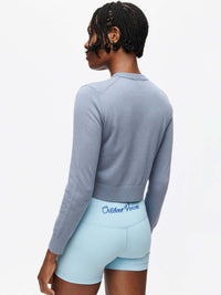 Back view of Sugar Cardigan in Soft Blue, lightweight knit fabric styled with active shorts.