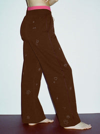Side view of model wearing Sunny Sweatpant in Brown with a technical nylon waistband and playful graphic details.