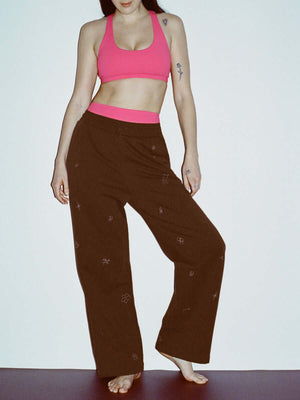Model wearing Sunny Sweatpant in Brown with wide leg design and embroidered flower details, styled for lounging.