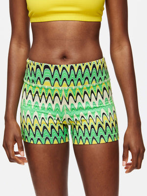Model wearing vibrant TechSweat 3" Short with a pattern of green waves and a yellow top, for workouts.