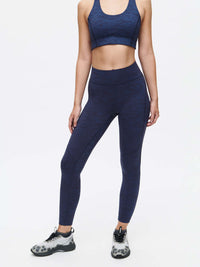 Model in a dynamic pose wearing TechSweat Core 7/8 Legging in Navy, with a supportive, engineered waistband.