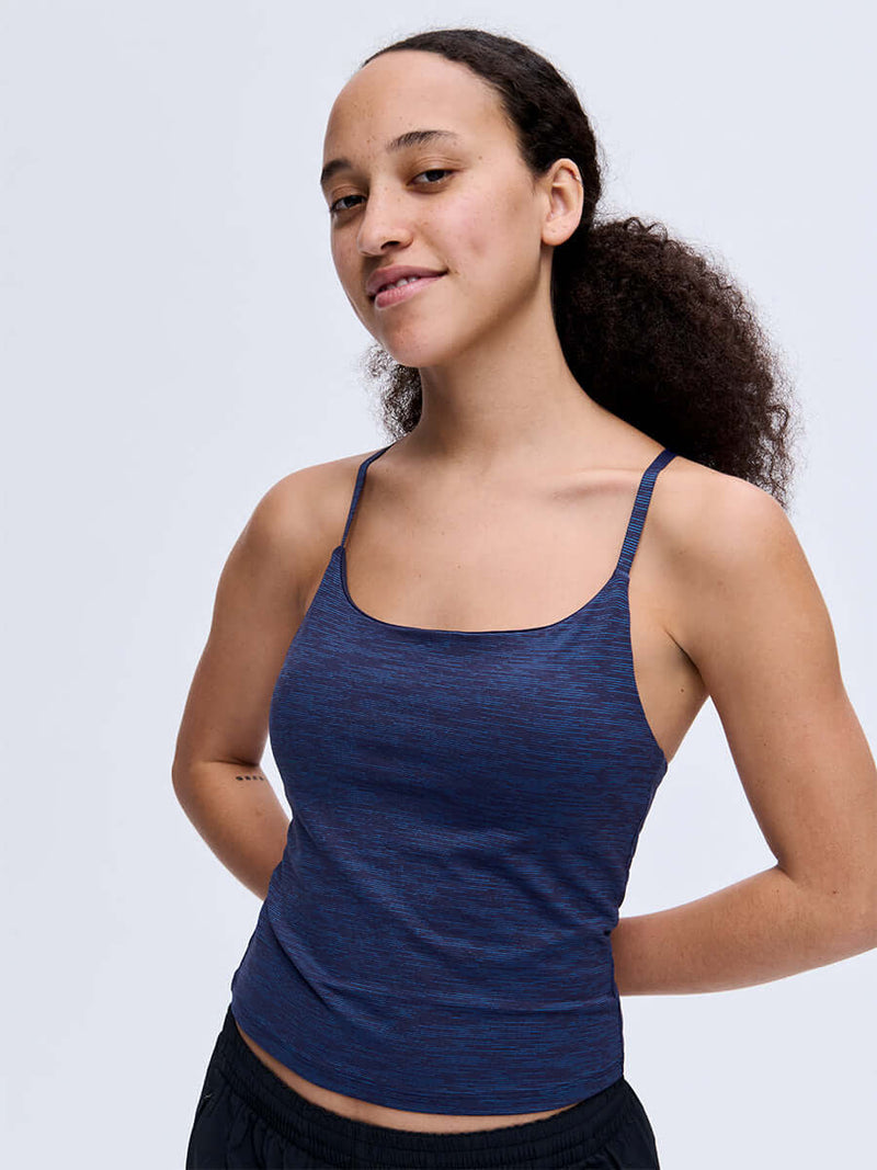 Model smiling in TechSweat Move Free Tank in Navy, featuring adjustable racerback straps.
