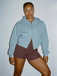 Model wearing The Diamanté Doing Things Hoodie in Light Blue, featuring diamante script and cropped design.