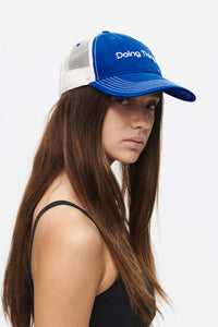 Profile view of a woman wearing a Doing Things Trucker Hat in blue, with style and comfort.