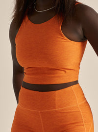 Model wearing Venus Crop Top in vibrant orange, featuring a light support design and cropped length.