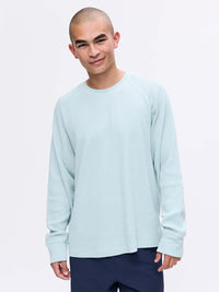 Model smiling in Waffle Longsleeve in light blue, featuring a relaxed fit and soft waffle knit fabric.