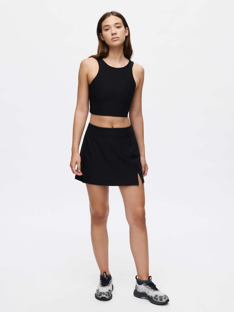 Model in black warmup 2.5" skort with a side split, styled for active movement.