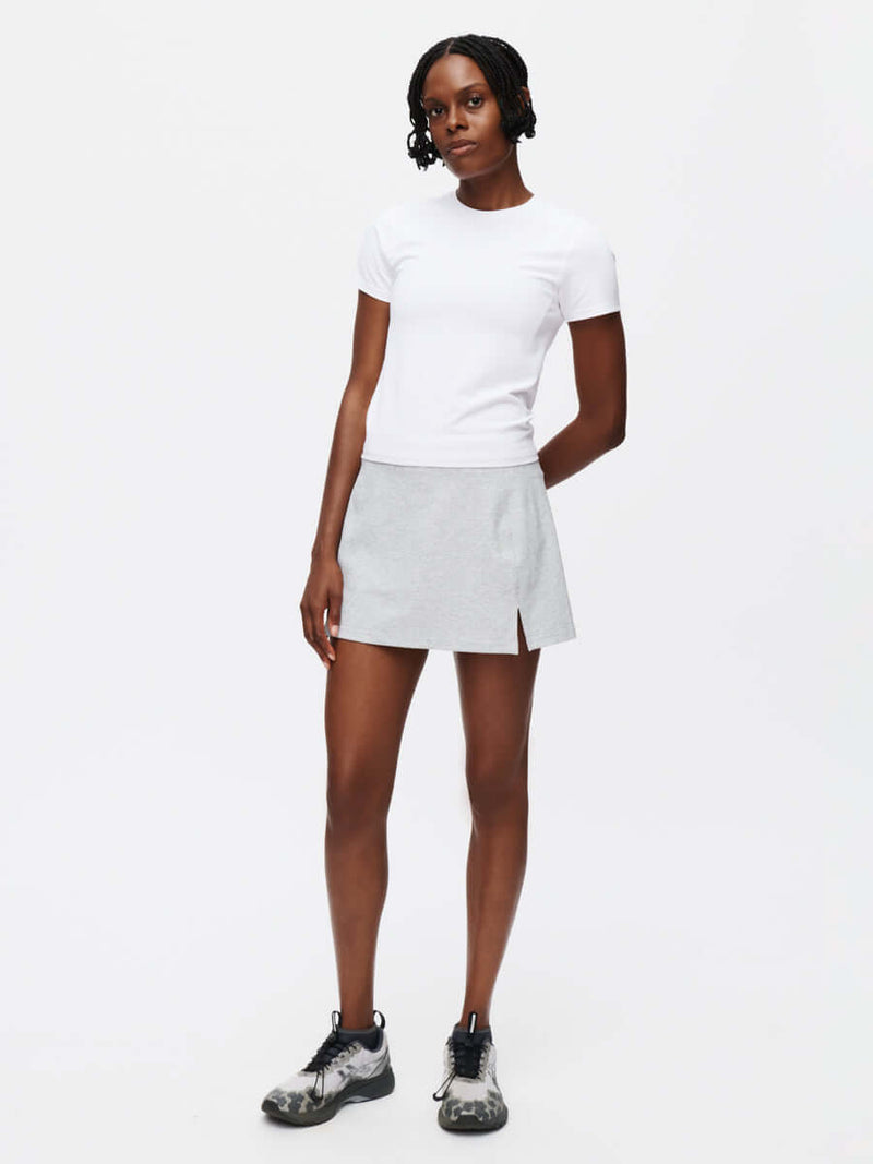 Model standing in Warmup 2.5" Skort in Gray, featuring a side slit for ease of movement.