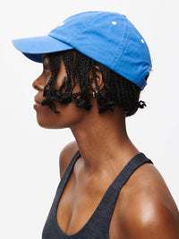 Profile view of model wearing Washed Hat in blue, made from 100% washed cotton with a curved brim.