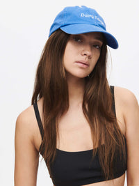 Model wearing Washed Hat in blue, soft washed cotton with curved brim and Doing Things embroidered.