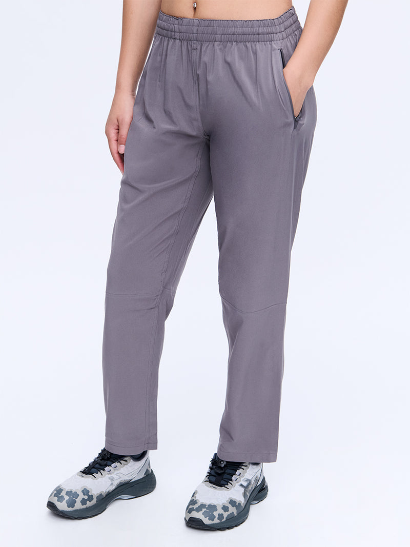 Model standing in Zephyr 26" Pant in Grey, designed with a custom-fit drawstring waist and zippered pockets.