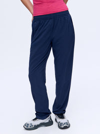 Model in pink top wearing Zephyr 29" Pant in Navy, featuring a custom-fit drawstring waist.